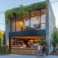 two people are standing in front of a building with plants growing on the side of it