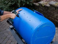 a man is working on a large blue barrel