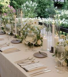 the table is set with wine glasses, silverware and flowers