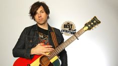 a man holding a red and yellow guitar