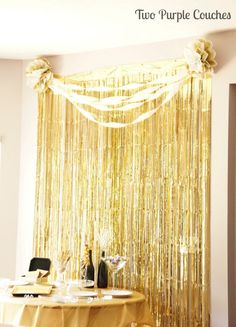 the table is set up for a wedding reception with gold foil curtain and flowers on it