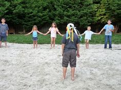 a group of children holding hands in the sand