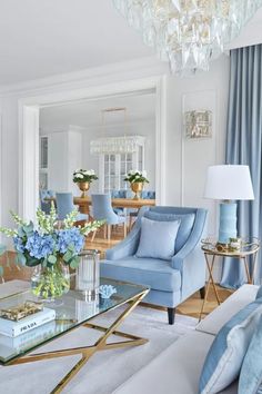 a living room filled with furniture and a chandelier above a glass coffee table