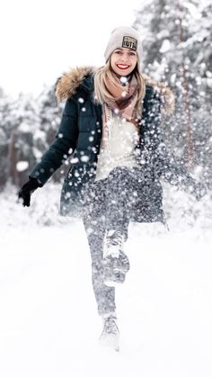 a woman is walking through the snow with her hat on and she has one foot in the air