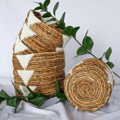 three woven baskets sitting next to each other on top of a white cloth covered table