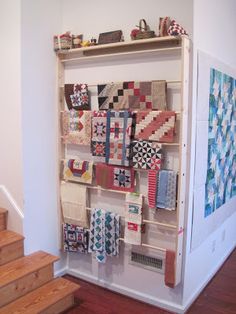 there is a shelf with many quilts on it in the room next to some stairs