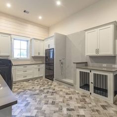 an empty kitchen with white cabinets and tile flooring