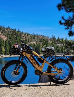 a bike parked next to a lake with mountains in the background