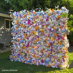 a wall made out of flowers in front of a house