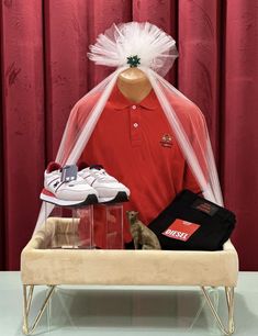 a mannequin wearing a red shirt and white tulle with shoes in it