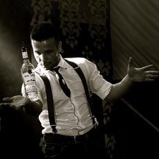 a man wearing suspenders and a tie holding a bottle of alcohol in his hands