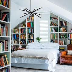 a bed sitting in a bedroom next to a book shelf filled with lots of books