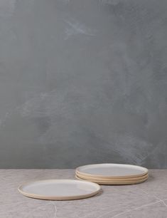 two white plates sitting next to each other on top of a gray tablecloth covered floor