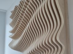 an intricate wooden sculpture is hanging from the ceiling in front of a wall with wavy lines on it