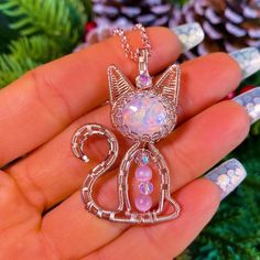 a person holding a pink cat pendant in their hand