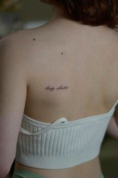 the back of a woman's shoulder with a small tattoo on her left side