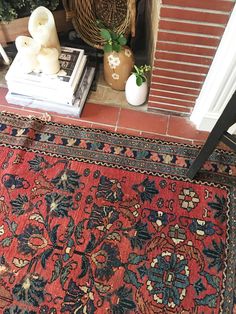 a red rug sitting on top of a wooden floor next to a fire place filled with books