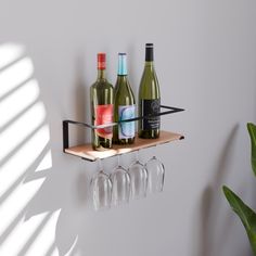 three wine glasses are sitting on a shelf next to bottles and two empty wine glasses