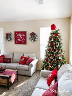 a living room decorated for christmas with red and white decorations on the walls, couches, coffee table and tree