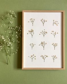 some flowers are sitting on a table next to a framed photo and a vase with baby's breath