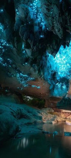 the inside of a cave with blue lights and water in it's pool area