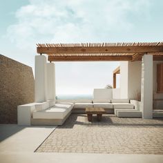 a white couch sitting on top of a patio next to a wooden pergoline