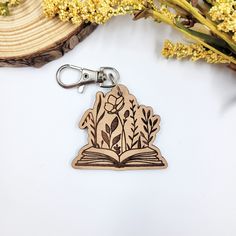 a wooden keychain with an open book and flowers