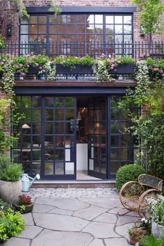 the front entrance to a brick building with lots of plants and flowers growing on it