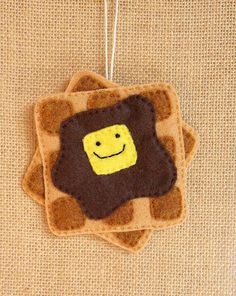 a felt ornament with a smiling face on it's side, hanging from a string