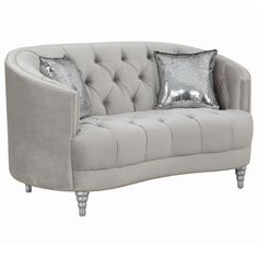 a gray couch with two pillows on it and some silver sequins around the cushion