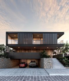 two cars are parked in front of a modern house with large windows and balconies