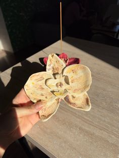 a person holding up a flower on top of a wooden table