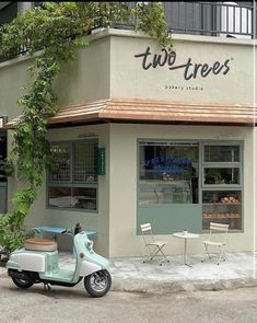 a scooter parked in front of a store with two trees on the side