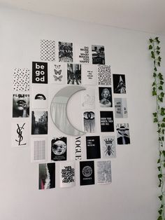 a white wall covered in lots of black and white stickers next to a plant