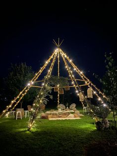 a large tent with lights on it in the middle of a yard at night time