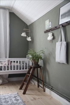 a baby's room with green walls and white trim, including a wooden ladder