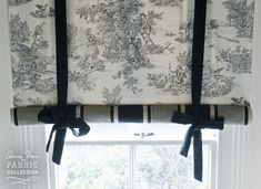 a window with black and white curtains hanging on it's side in front of a window