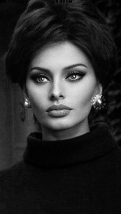 a black and white photo of a woman with large earrings on her head, looking at the camera