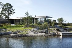 a house sitting on top of a lush green hillside next to a body of water