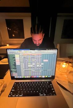 a man sitting in front of a laptop computer on top of a table with utensils