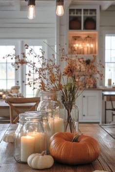 candles and pumpkins are sitting on a wooden table in front of the kitchen counter