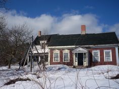 an old red house with snow on the ground