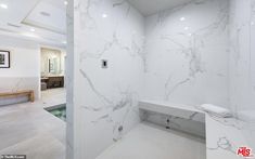 a white bathroom with marble walls and flooring