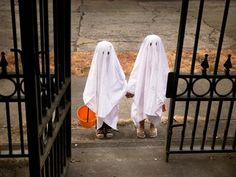 two people in white ghost costumes standing behind gates