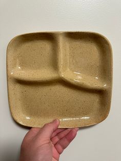 a person holding up a square shaped plate