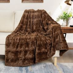 a living room with a white couch and brown blanket on top of it's back