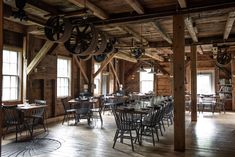 the inside of a restaurant with wooden tables and chairs, wood beams and large windows