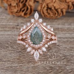 an emerald and diamond ring sitting on top of a wooden table