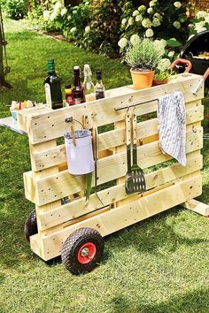 a wooden cart with utensils on it in the grass next to some plants