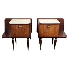 a pair of nightstands with marble top and wooden legs, one on each side